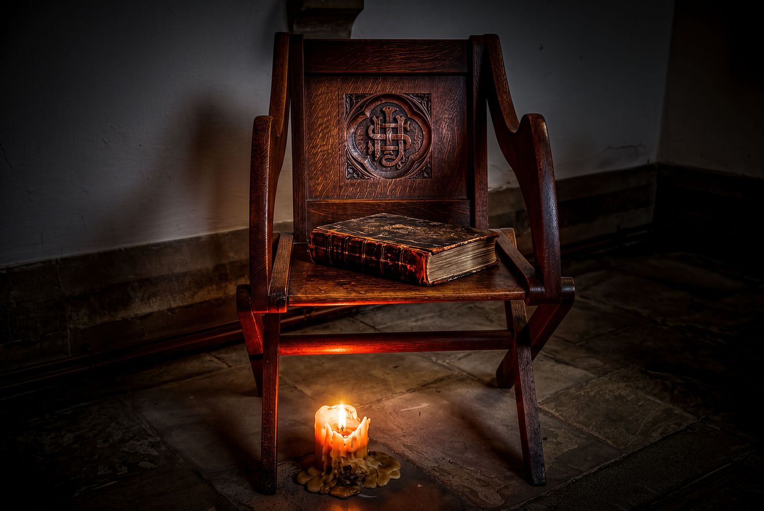Antique carved wooden chair with an old book on the seat, lit by a single candle on a stone floor.