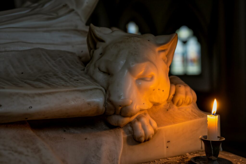 A marble lion rests in peaceful repose, illuminated by the flickering warmth of a single candle
