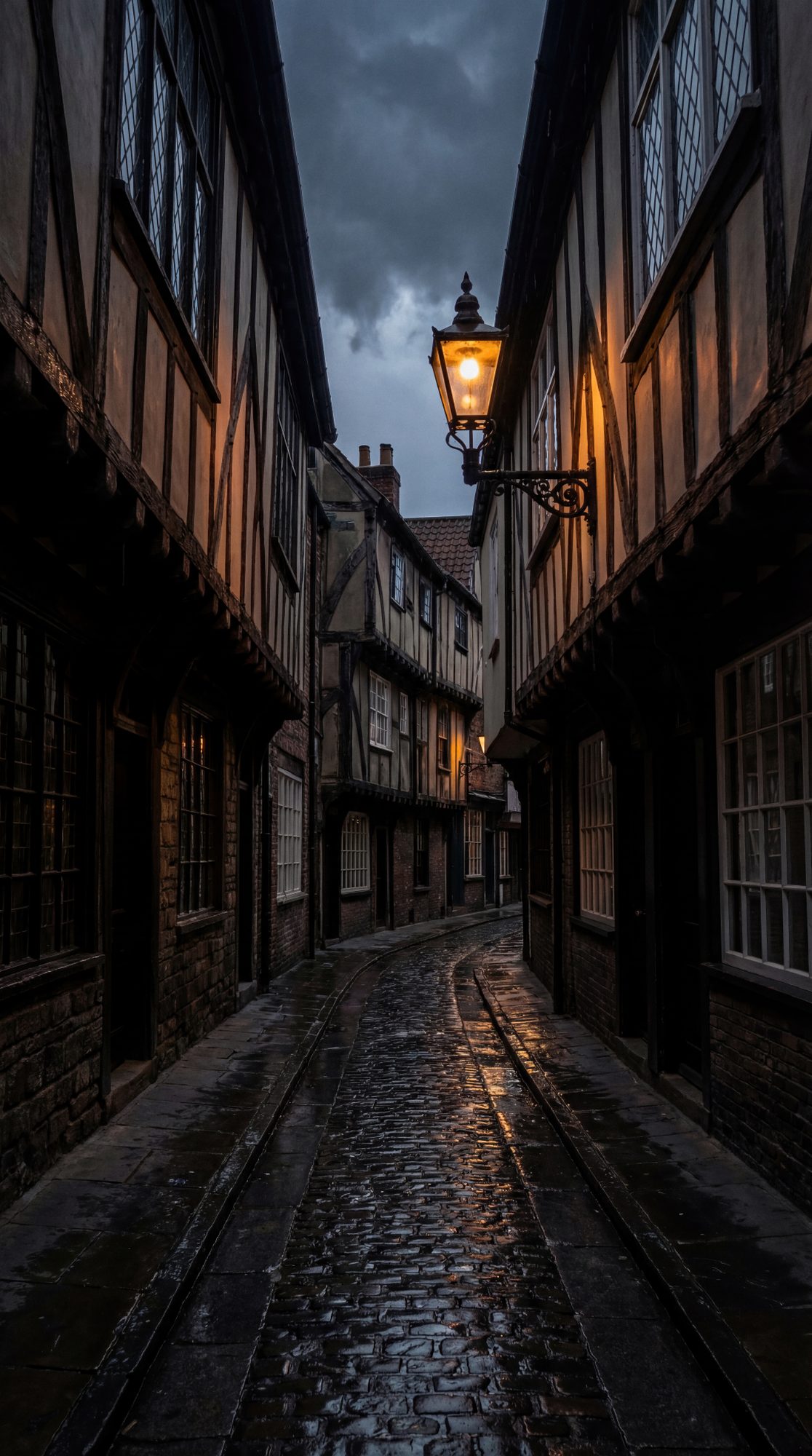 A narrow medieval street curves into shadow, lit only by a lonely lantern reflecting off the wet cobblestones