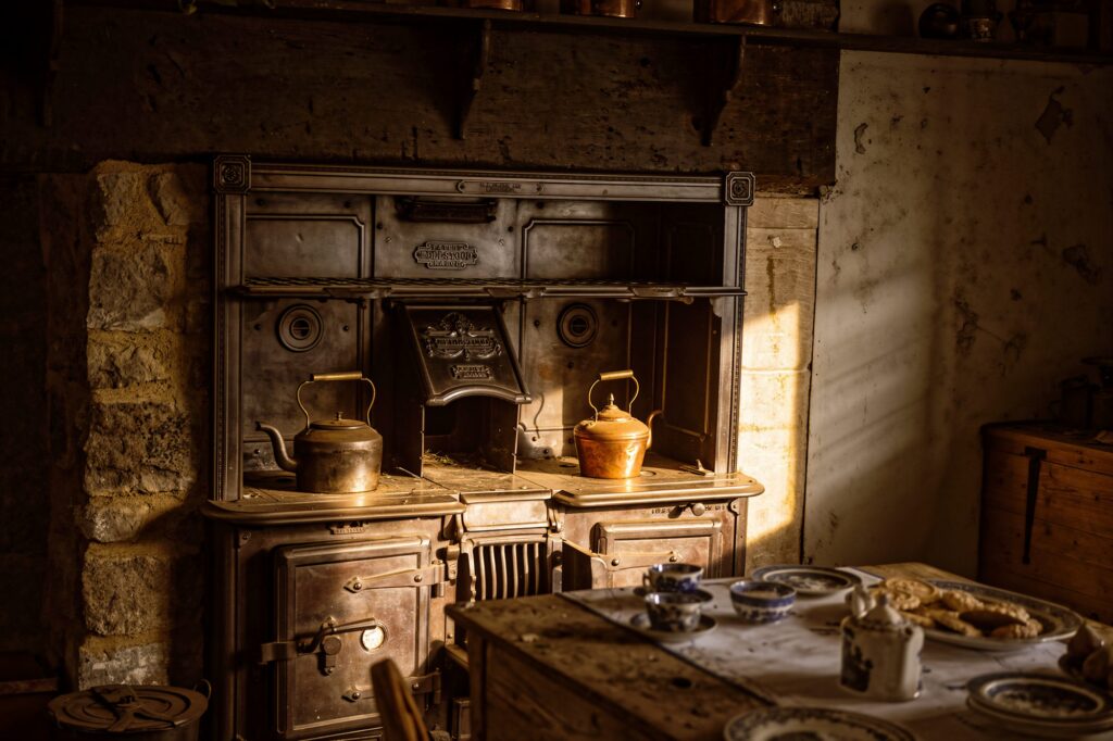 The Sunlit Range. Strong morning light falls across an old black range cooker, catching the brass and copper kettles that sit on its surface